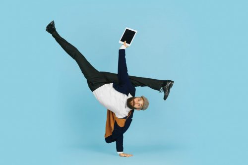 Young,Caucasian,Businessman,Having,Fun,Dancing,Break,Dance,On,Blue flexibel tarif mann handstand tablet scaled 500x0 c default