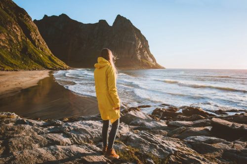 Woman,In,Yellow,Raincoat,Walking,Alone,On,Kvalvika,Beach,In shutterstock 1782385076 scaled 500x0 c default